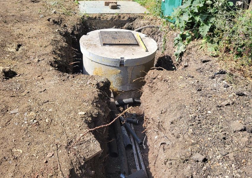 New chamber cover at ground level with the pipe trench beside it