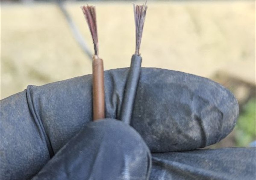 Two cable ends with exposed wires held in a gloved hand