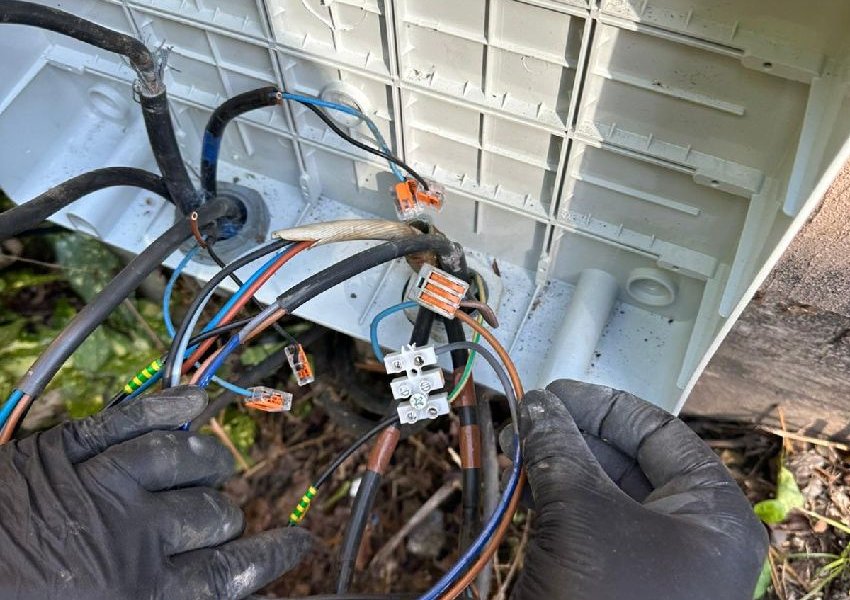 Gloved hands wiring connectors in an open junction box