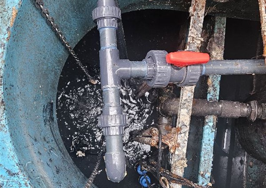 Grey pipework with a red-handled shut-off valve inside a pump chamber near Cobham