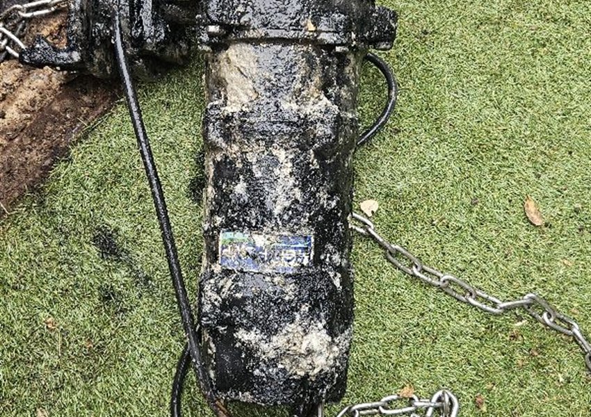 Submersible pump lifted out of a chamber on a lifting chain