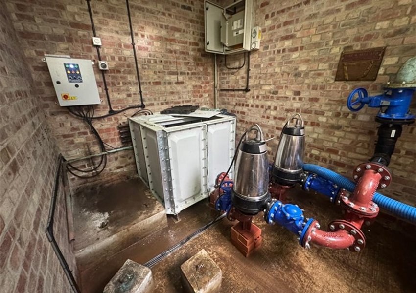 Completed pump chamber with two pumps, valves, a tank and a control panel on the wall