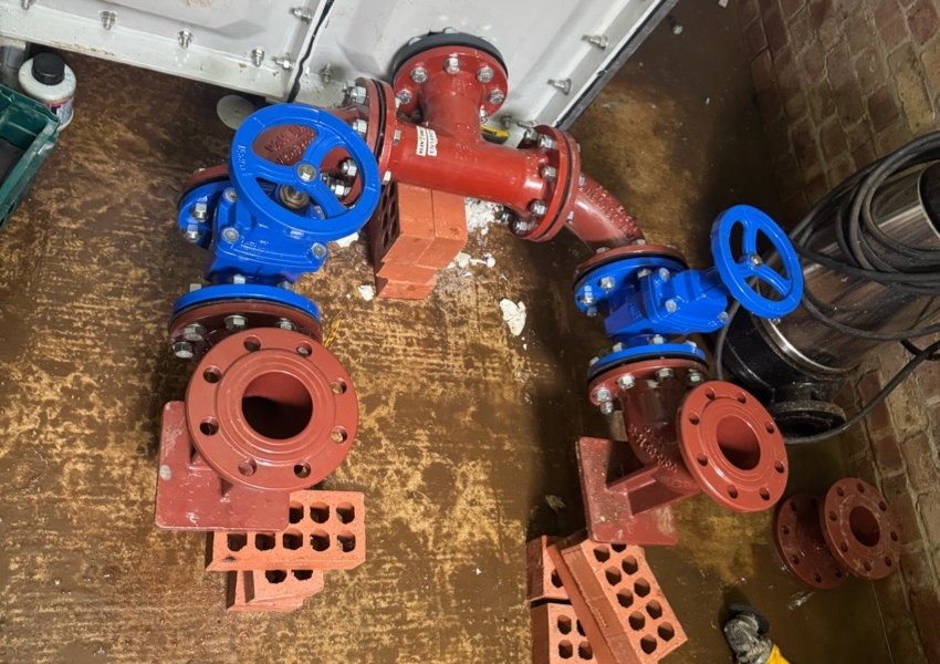 Red and blue DN100 valves and bends laid out before installation