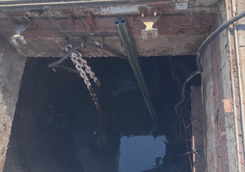 Looking down into a pump chamber with a lifting chain and guide rails