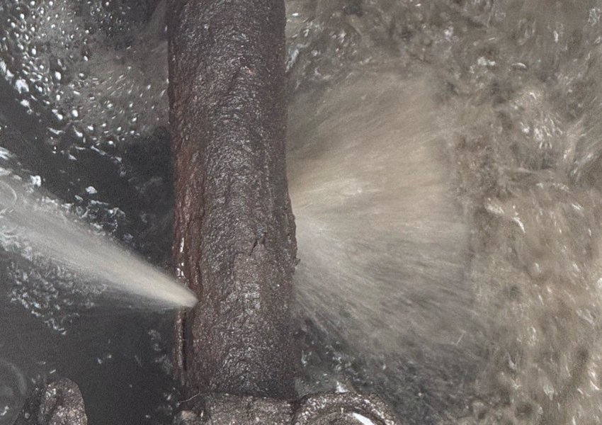 Water spraying from a split in old pipework inside a valve chamber