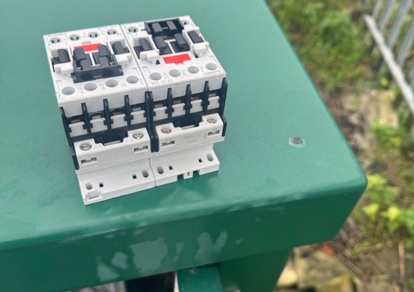 Pair of new contactors standing on a green panel cabinet
