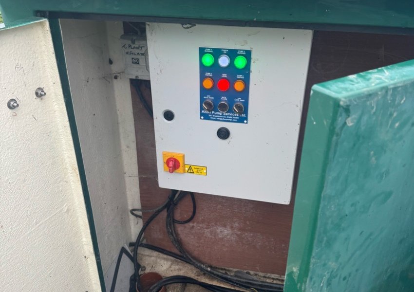 Pump control panel with status lights inside a green cabinet