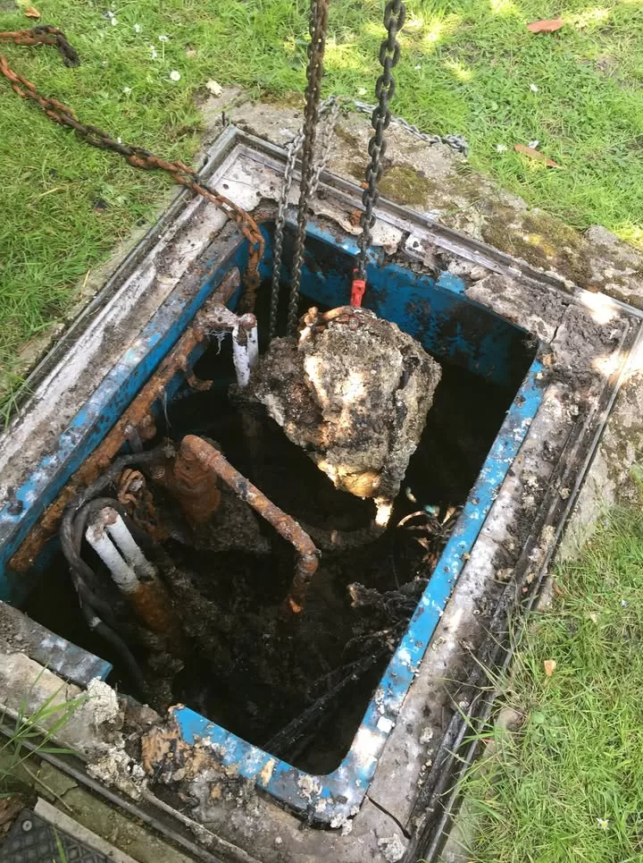 A submersible pump being lifted from a chamber encased in solidified grease