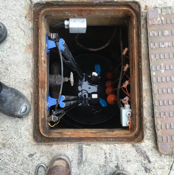 View of a pump station chamber with new pumps and guide rails installed